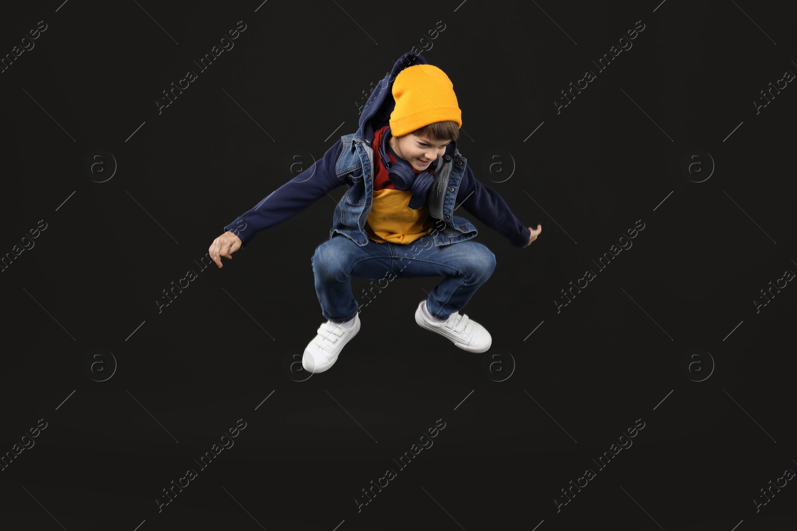 Photo of Happy little boy jumping on black background