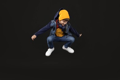 Photo of Happy little boy jumping on black background