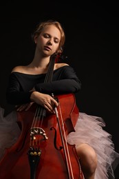 Photo of Beautiful young woman with cello on black background