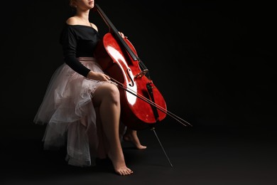 Photo of Young woman with cello on black background, closeup. Space for text