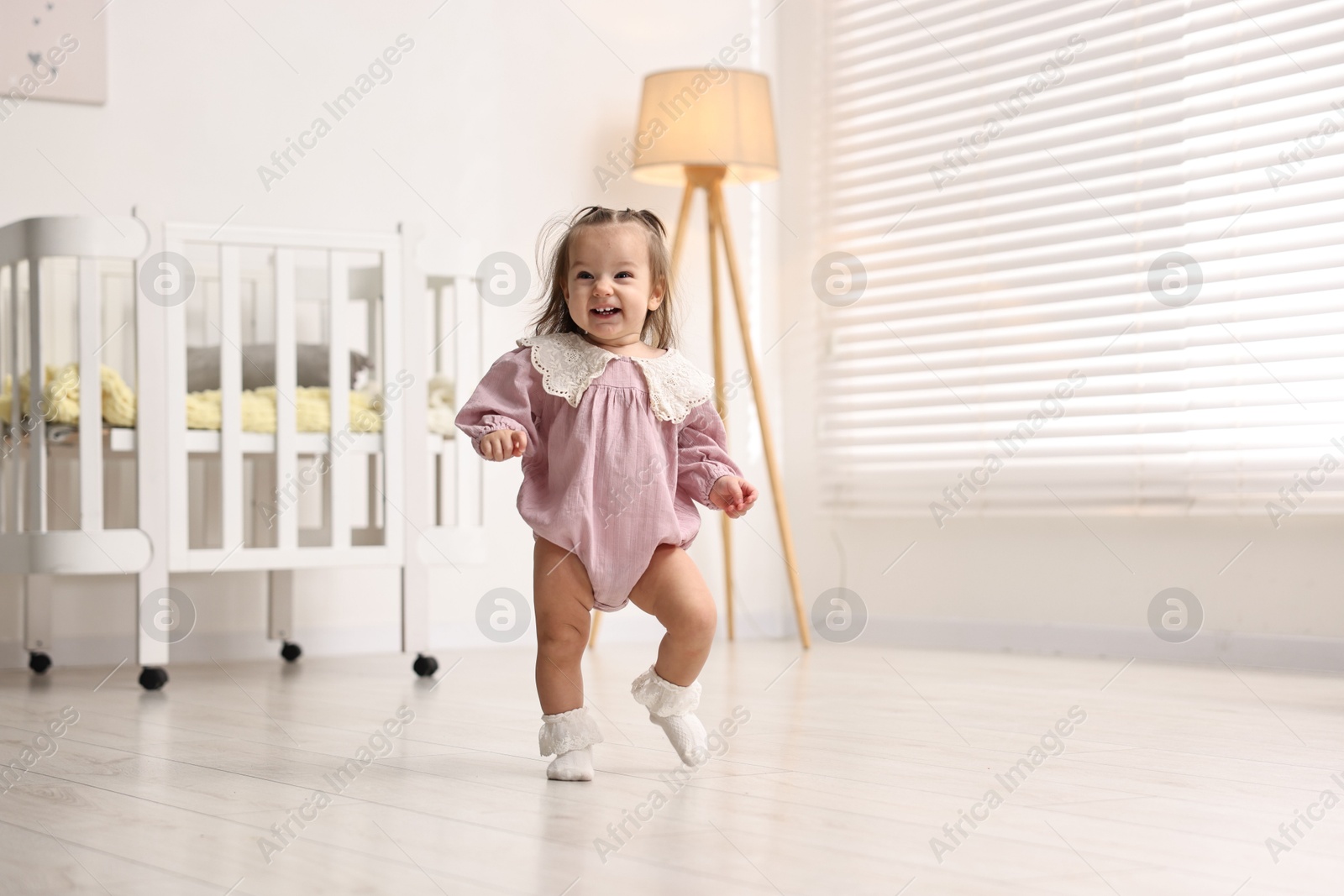 Photo of First steps. Cute little baby learning to walk at home