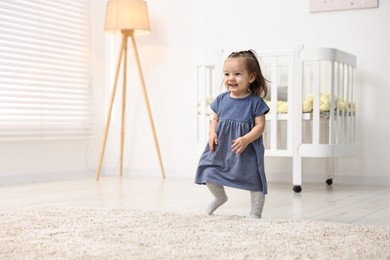 Photo of First steps. Cute little baby learning to walk at home, space for text