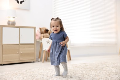 Photo of First steps. Cute little baby learning to walk at home