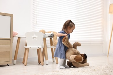 Photo of First steps. Cute little baby with teddy bear at home