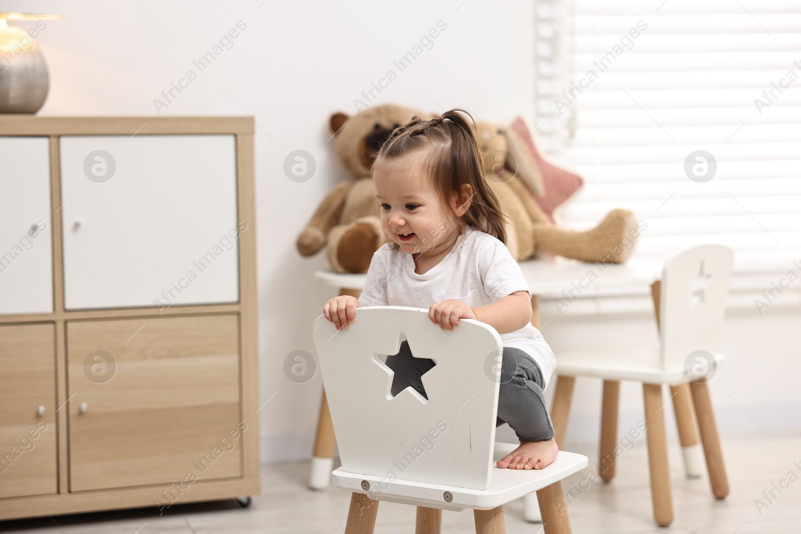 Photo of First steps. Cute little baby on small chair at home