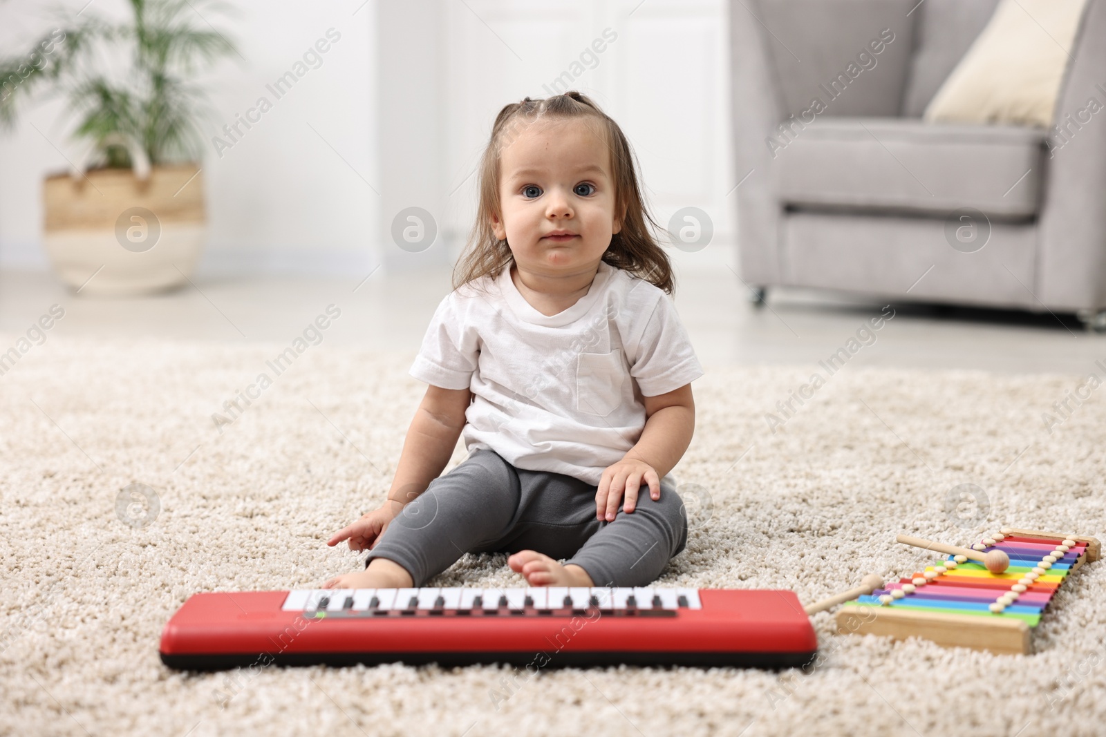 Photo of Cute little girl playing with toy piano at home