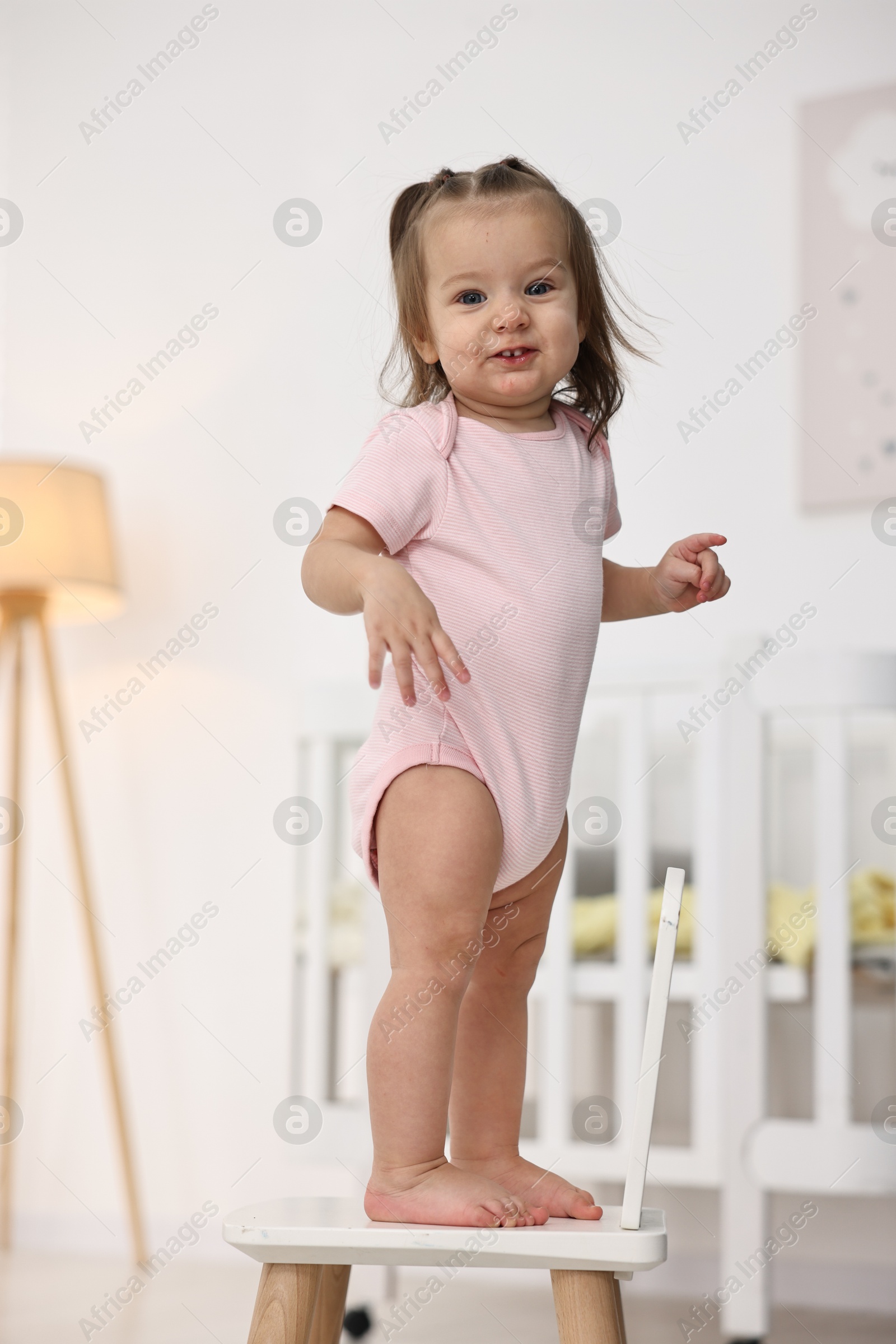 Photo of First steps. Cute little baby on small chair at home