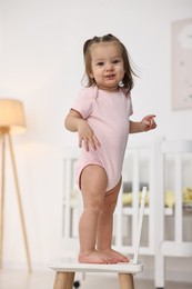 Photo of First steps. Cute little baby on small chair at home