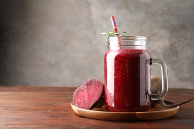 Photo of Fresh beetroot smoothie in mason jar and vegetables on wooden table, closeup. Space for text