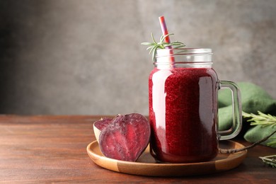 Photo of Fresh beetroot smoothie in mason jar and vegetables on wooden table, closeup. Space for text