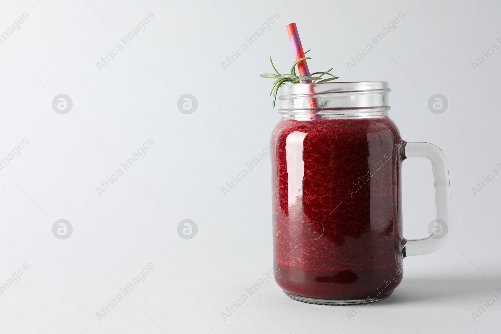 Photo of Fresh beetroot smoothie in mason jar on light background, closeup. Space for text