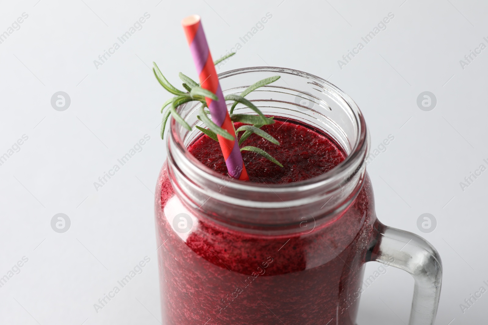 Photo of Fresh beetroot smoothie in mason jar on light background, closeup