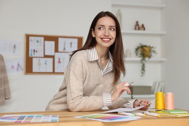 Fashion designer working at wooden table in workshop