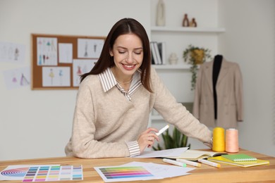 Fashion designer working at wooden table in workshop