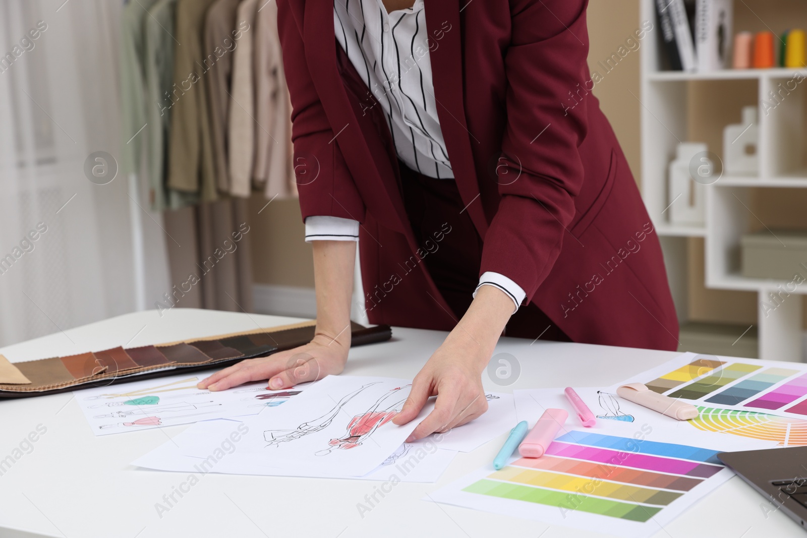 Photo of Fashion designer with sketches of clothes and color palettes working at white table in workshop, closeup