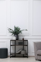 Photo of Console table with decor and pouf in room. Interior design