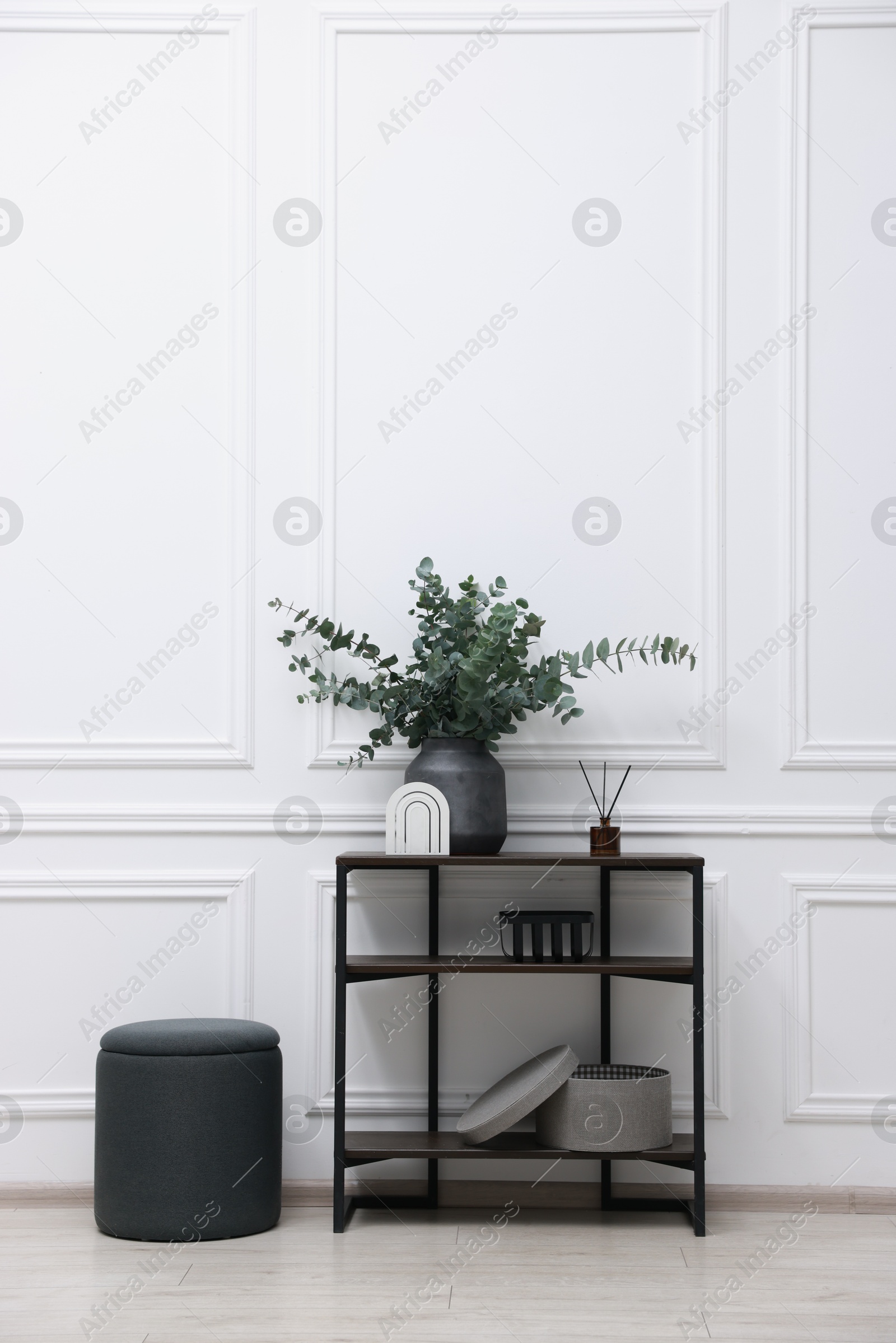 Photo of Console table with decor and pouf in room. Interior design