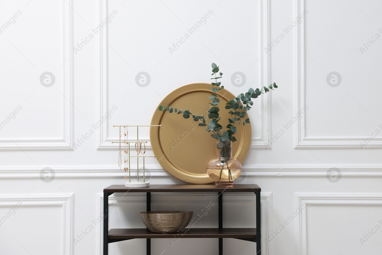 Photo of Console table with decor near white wall in room. Interior design