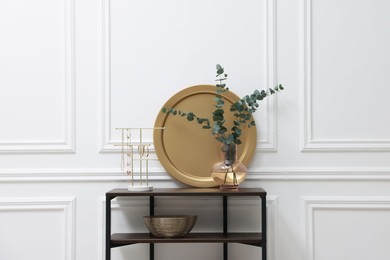 Photo of Console table with decor near white wall in room. Interior design