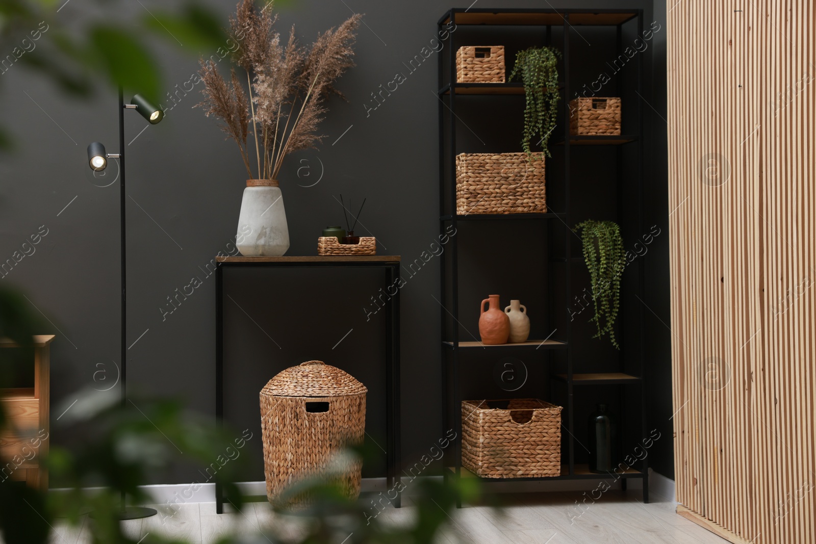 Photo of Console table with decor, lamp and shelving unit near grey wall in room. Interior design