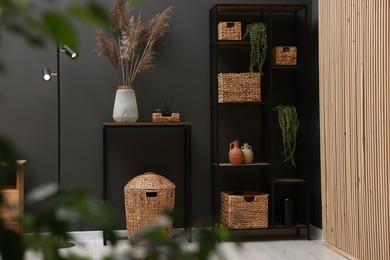 Photo of Console table with decor, lamp and shelving unit near grey wall in room. Interior design