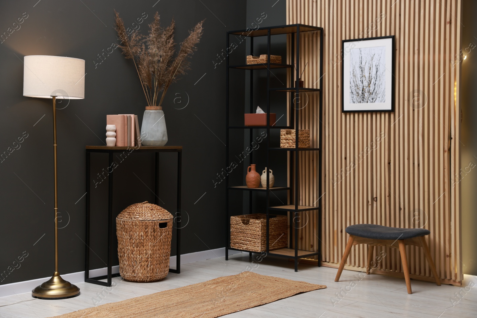 Photo of Console table with decor, lamp and shelving unit near grey wall in room. Interior design