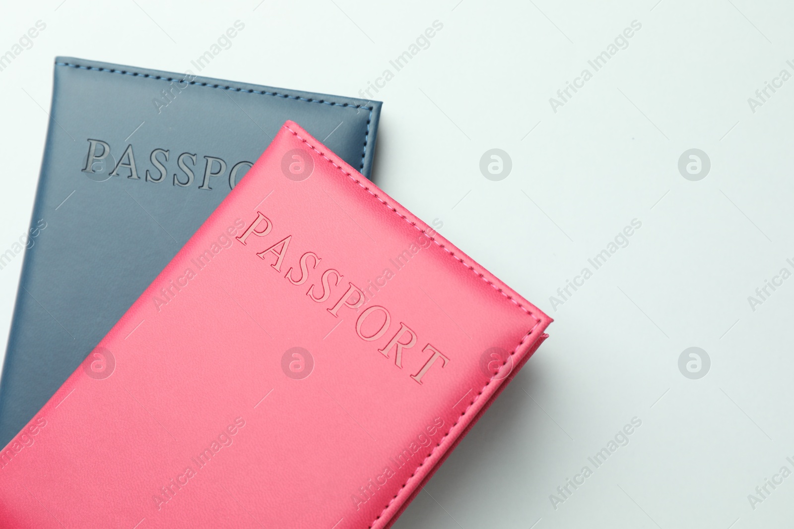 Photo of Passports in color covers on light background, top view. Space for text