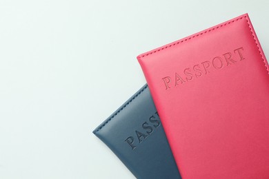 Photo of Passports in color covers on light background, top view. Space for text