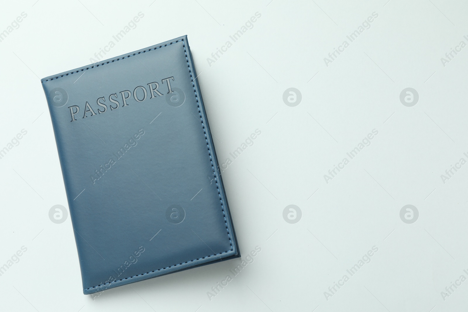 Photo of Passport in dark blue cover on light background, top view. Space for text