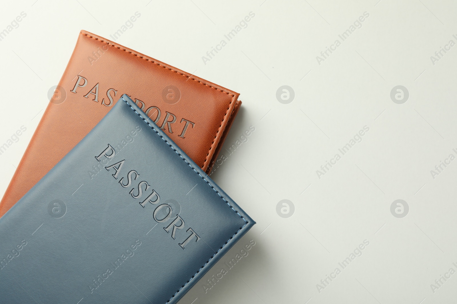 Photo of Passports in color covers on light background, top view. Space for text