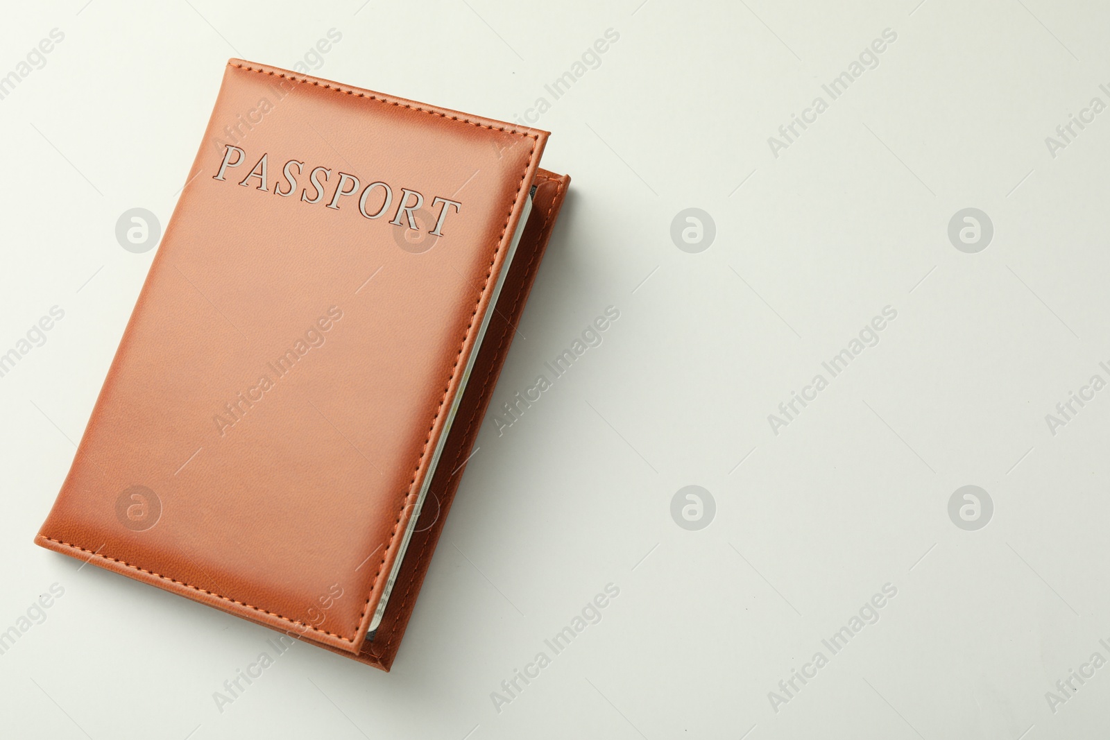 Photo of Passport in brown cover on light background, top view. Space for text