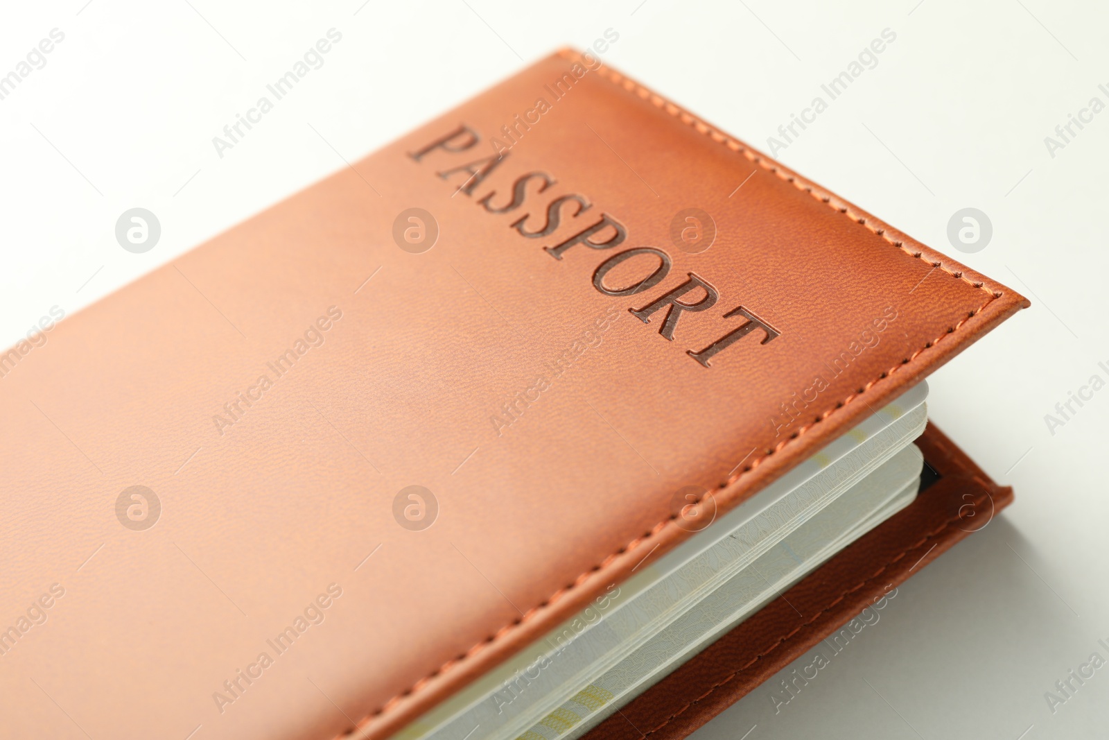 Photo of Passport in brown cover on light background, closeup