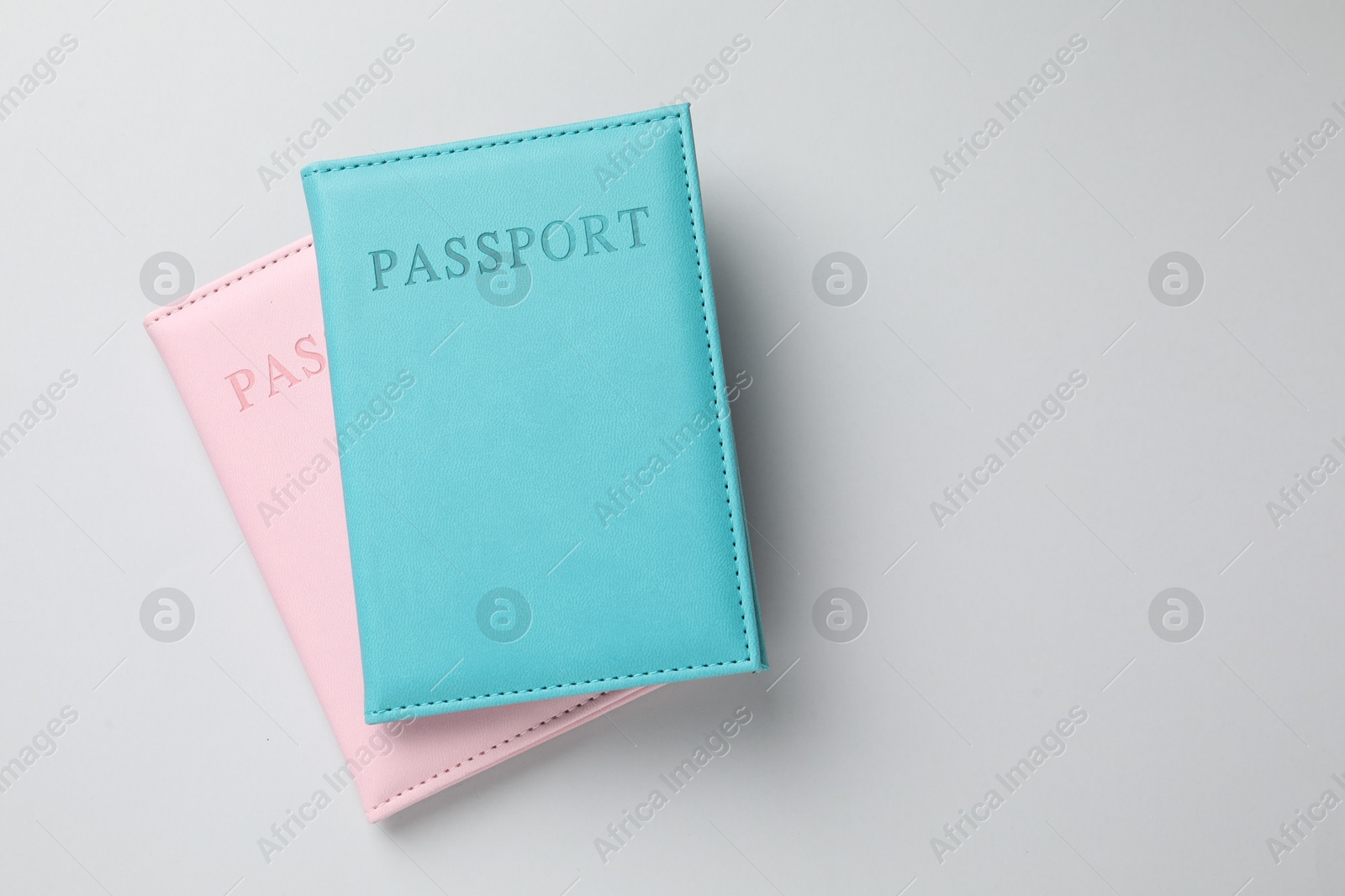 Photo of Passports in color covers on light background, top view. Space for text