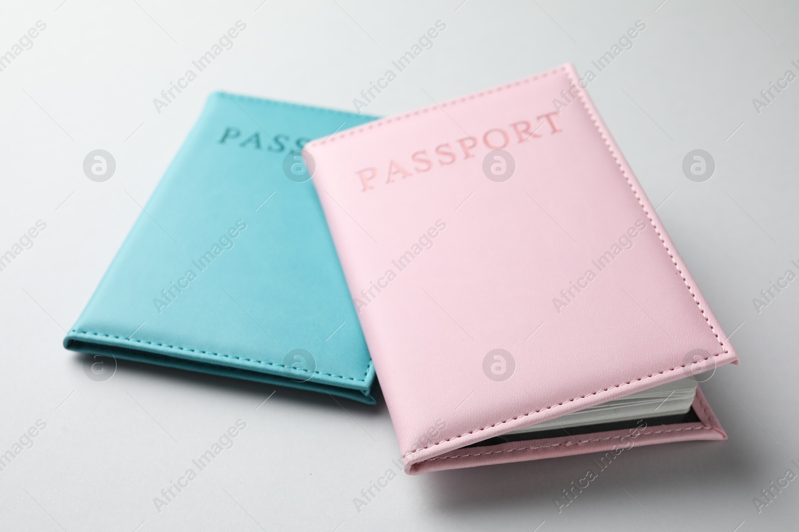 Photo of Passports in color covers on light background, closeup