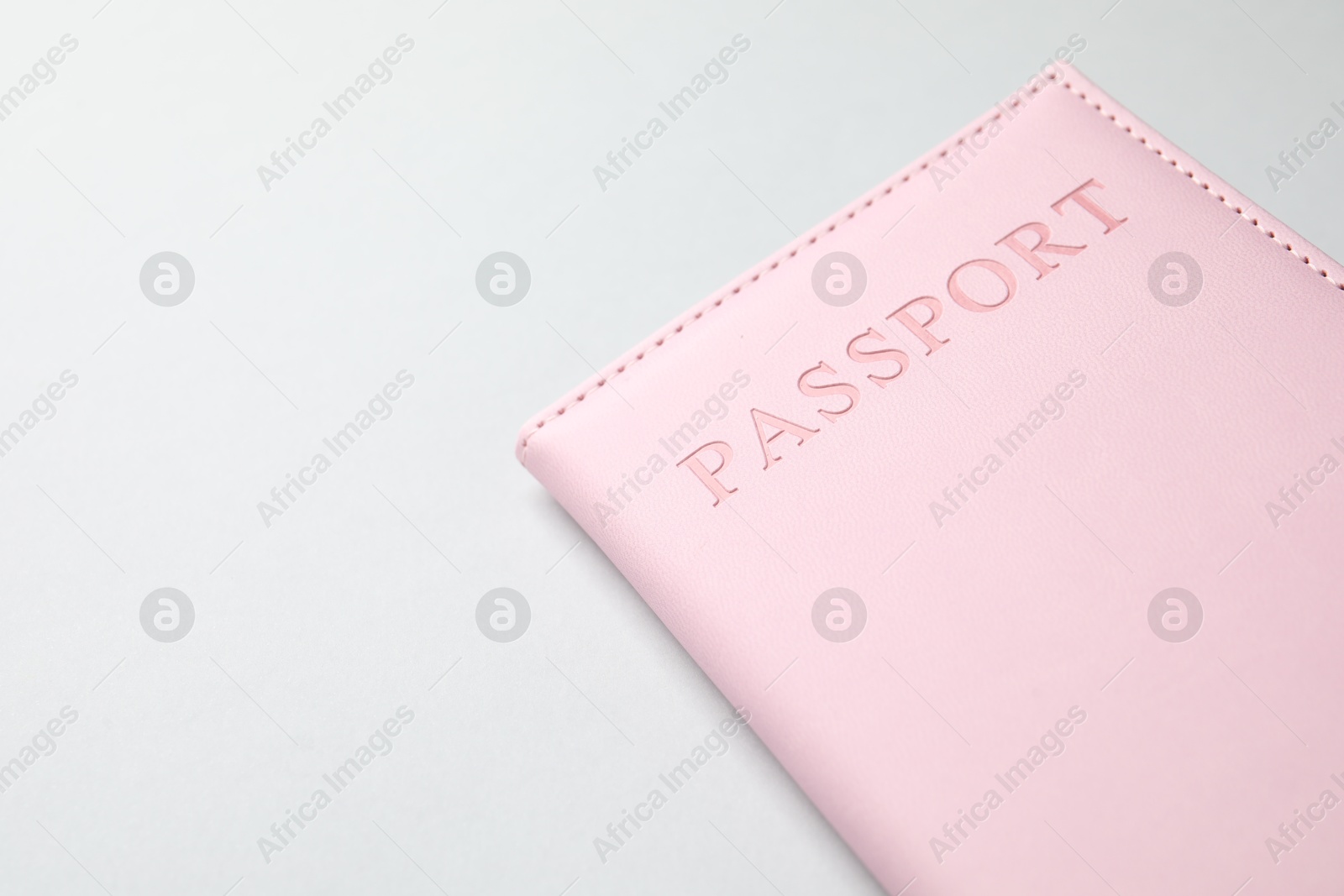 Photo of Passport in pink cover on light background, closeup. Space for text