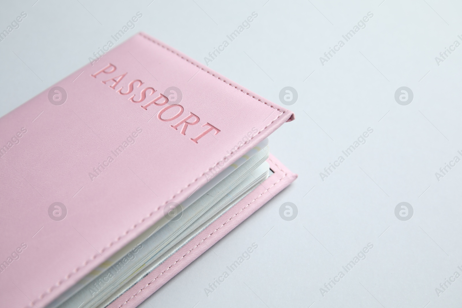 Photo of Passport in pink cover on light background, closeup. Space for text