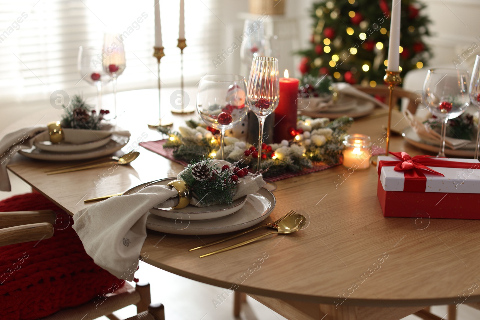 Photo of Christmas place setting with festive decor on wooden table in room