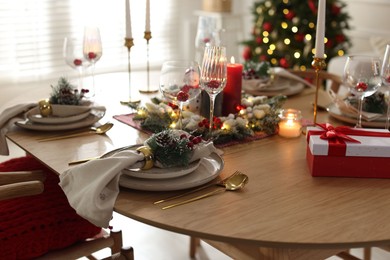 Photo of Christmas place setting with festive decor on wooden table in room