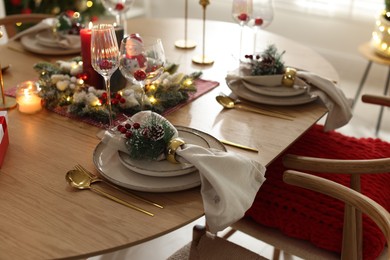 Photo of Christmas celebration. Festive table setting with dishware, glasses and decor in room