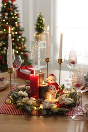 Photo of Christmas place setting with festive decor on wooden table in room