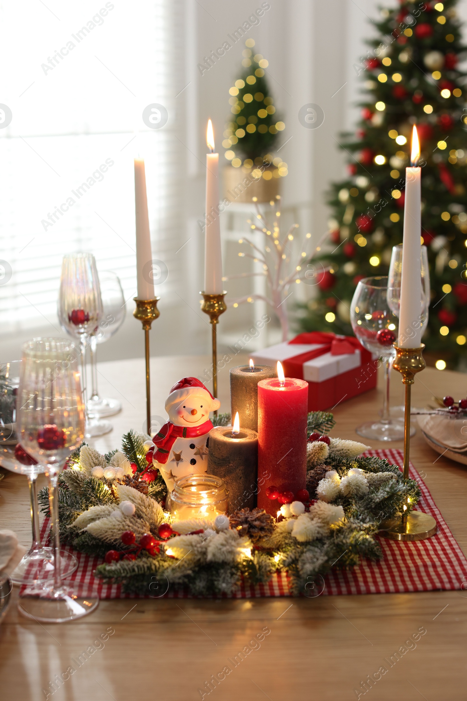 Photo of Christmas place setting with festive decor on wooden table in room