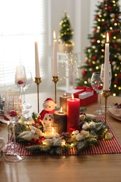 Photo of Christmas place setting with festive decor on wooden table in room