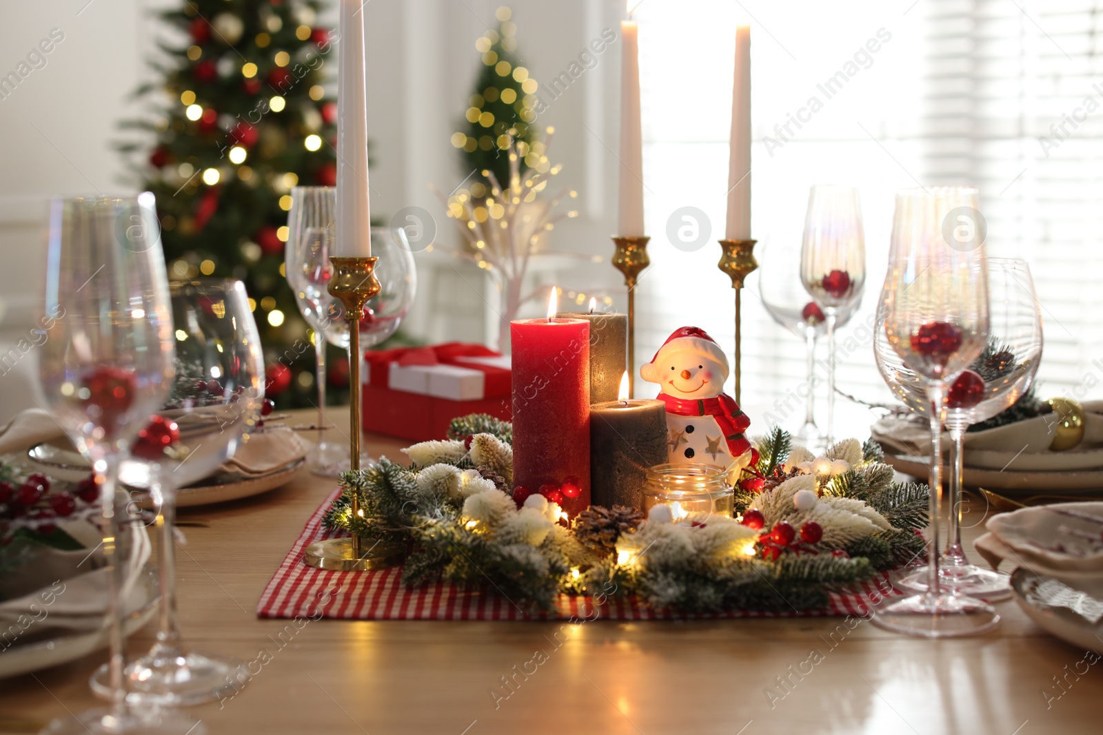 Photo of Christmas place setting with festive decor on wooden table in room