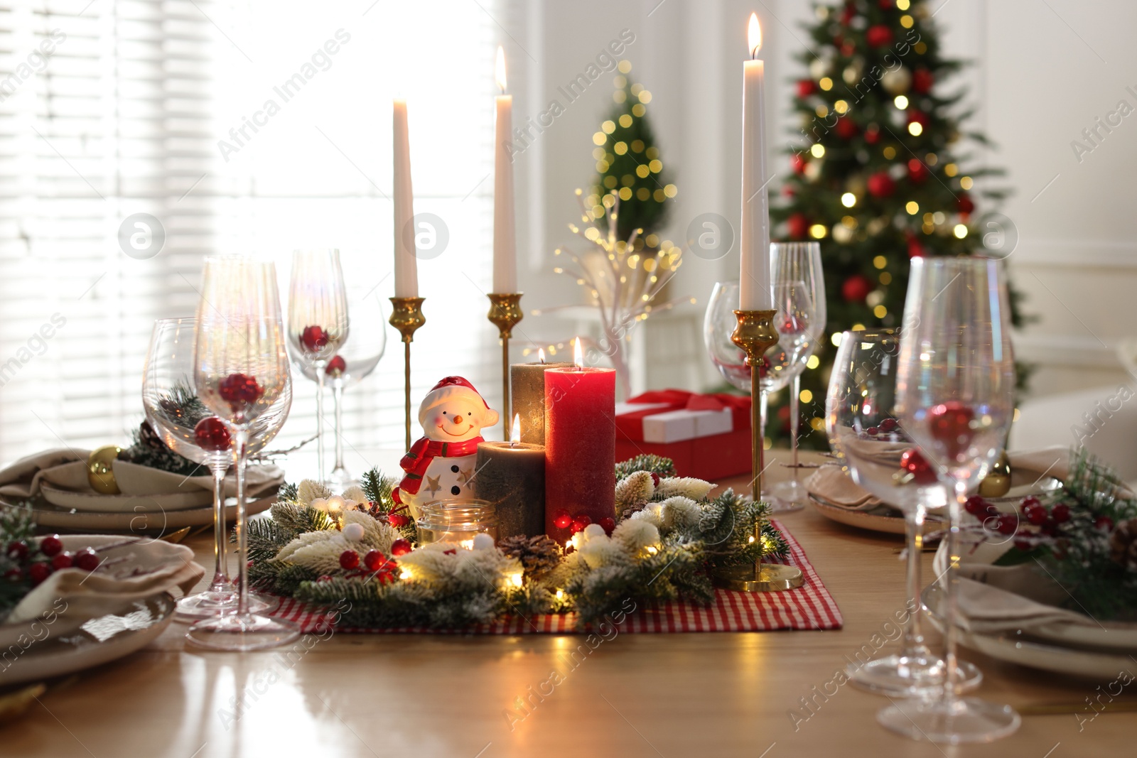 Photo of Christmas place setting with festive decor on wooden table in room