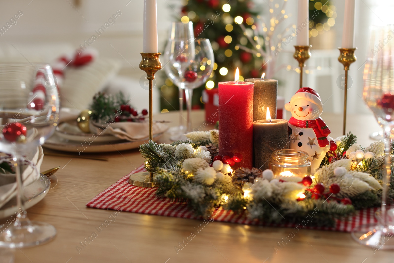 Photo of Christmas place setting with festive decor on wooden table in room