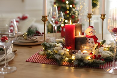 Photo of Christmas place setting with festive decor on wooden table in room