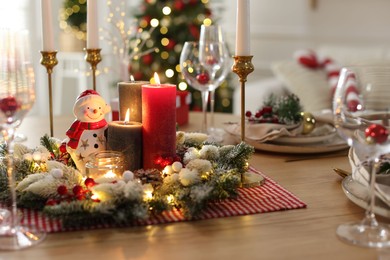 Photo of Christmas place setting with festive decor on wooden table in room