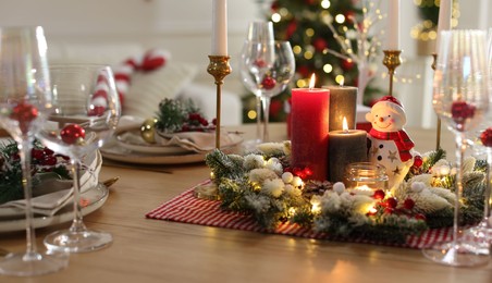 Photo of Christmas place setting with festive decor on wooden table in room