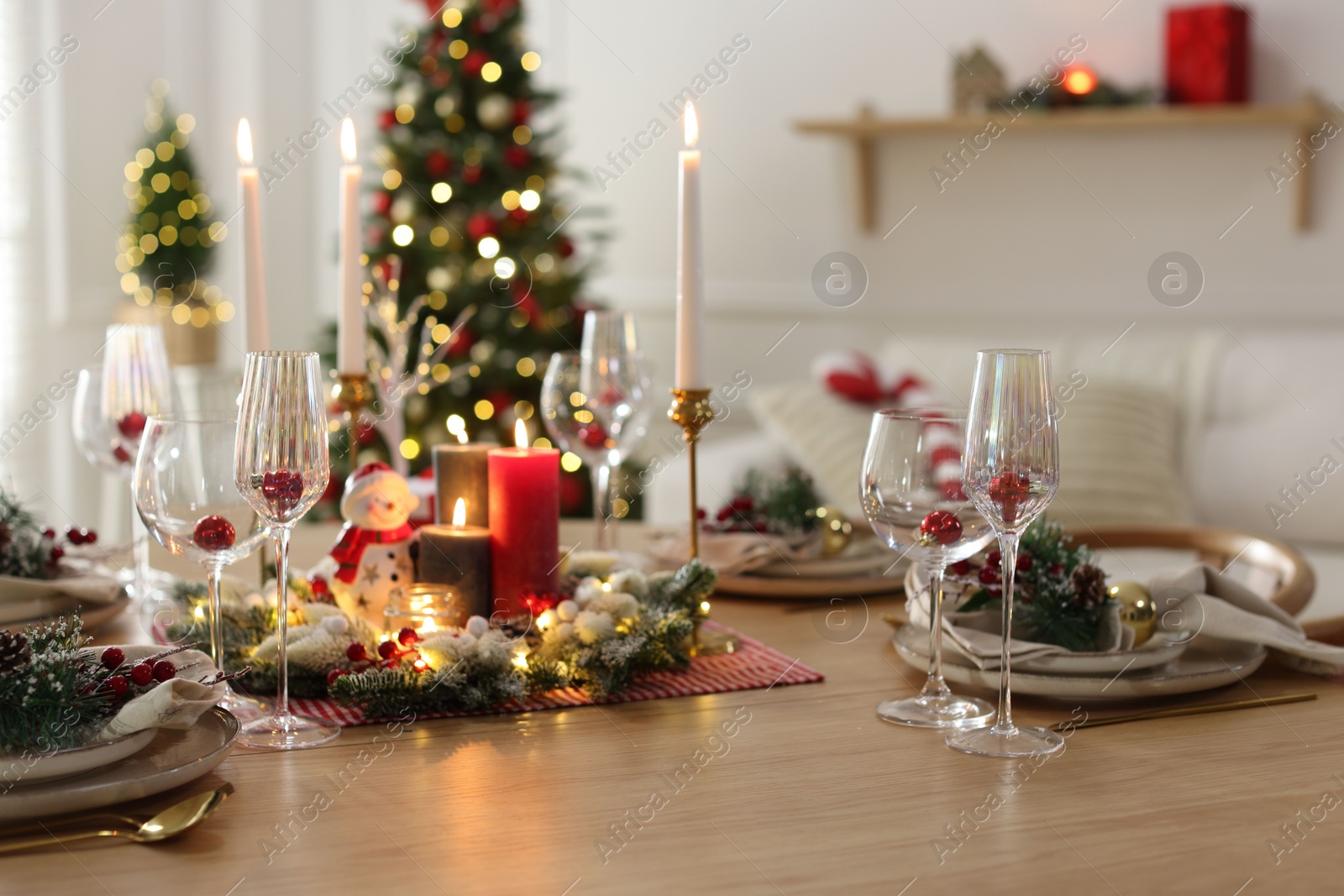 Photo of Christmas place setting with festive decor on wooden table in room