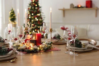 Photo of Christmas place setting with festive decor on wooden table in room